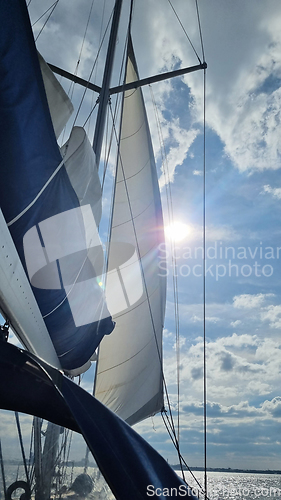 Image of Sailing yacht boat on seawater at sunrise with sun flare and outdoor lifestyle