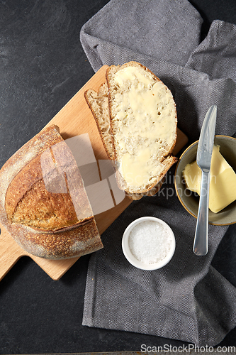 Image of close up of bread, butter, knife and salt on towel