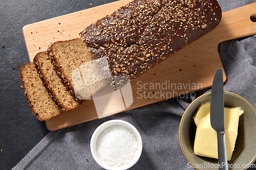 Image of close up of bread, butter, knife and salt on towel