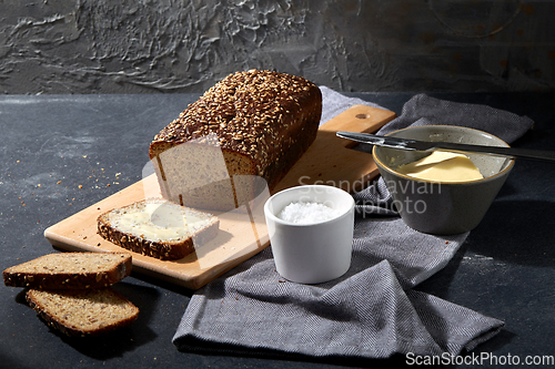 Image of close up of bread, butter, knife and salt on towel