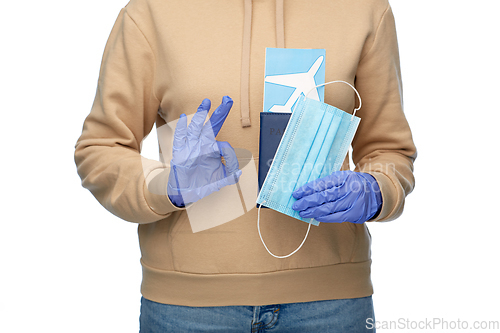 Image of woman with mask, passport and ticket shows ok sign