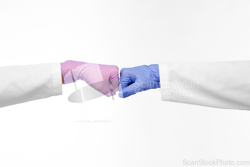 Image of hands of doctors in gloves make fist bump gesture