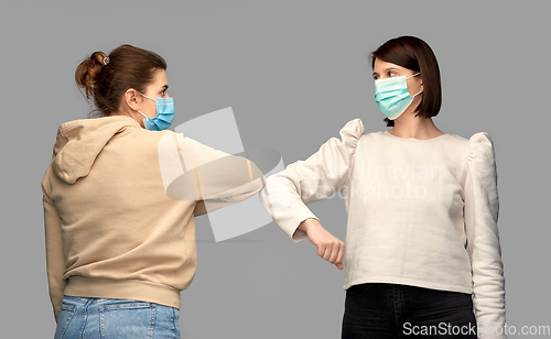 Image of women in masks making elbow bump greeting gesture