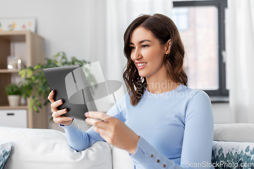 Image of happy smiling young woman with tablet pc at home