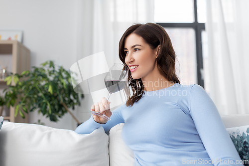 Image of happy woman drinking red wine at home