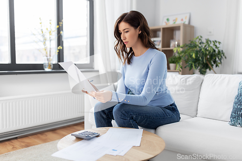 Image of woman with papers and calculator at home