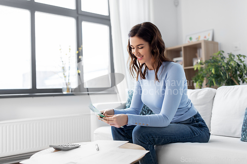 Image of happy woman counting money at home