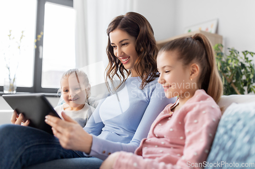 Image of happy mother and daughters with tablet pc at home
