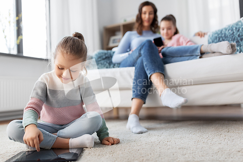 Image of happy girl with tablet pc and family at home