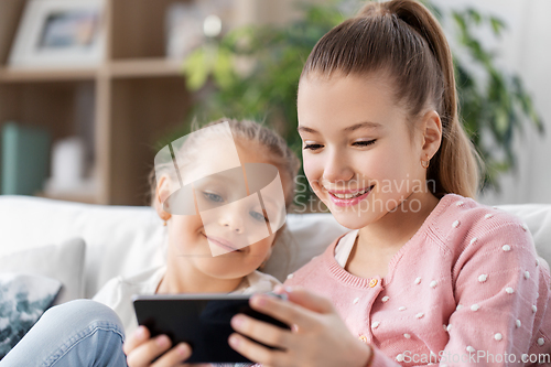 Image of happy little girls or sisters with phone at home