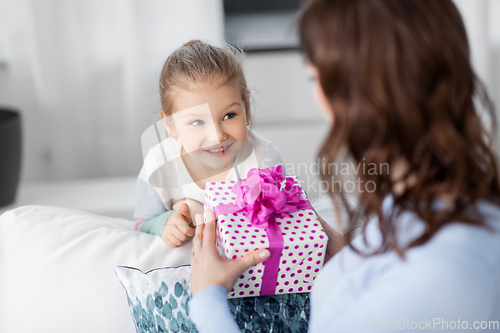 Image of happy daughter giving present to mother at home