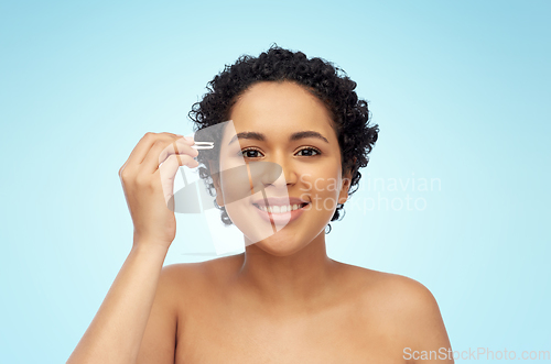 Image of african woman with tweezers tweezing her eyebrow