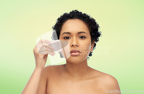 Image of young woman massaging her face with gua sha tool