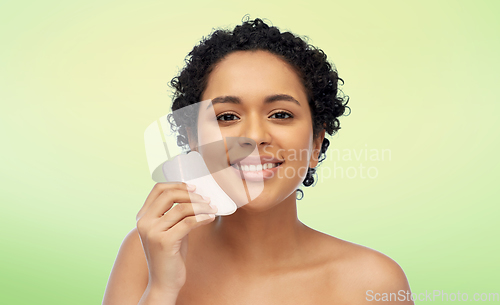 Image of happy woman massaging her face with gua sha tool