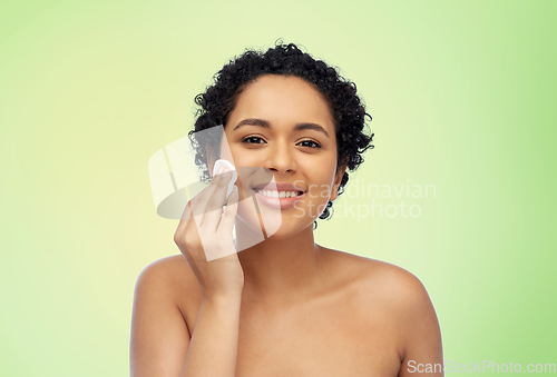 Image of happy african woman cleaning face with cotton pad