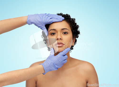 Image of face of african woman and hands in medical gloves