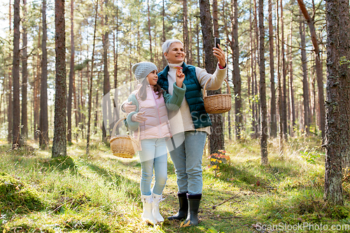 Image of grandma with granddaughter taking selfie in forest