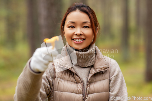 Image of young woman picking mushrooms in autumn forest