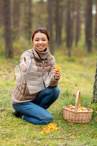 Image of woman with mushrooms showing thumbs up in forest