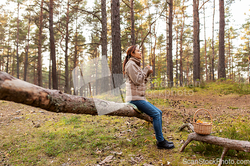 Image of asian woman with mushrooms drinking tea in forest