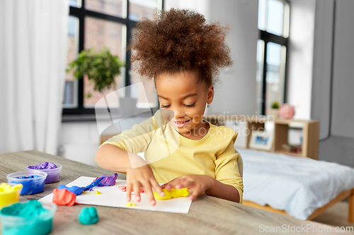 Image of little girl with modeling clay playing at home