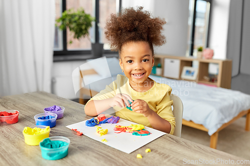 Image of little girl with modeling clay playing at home