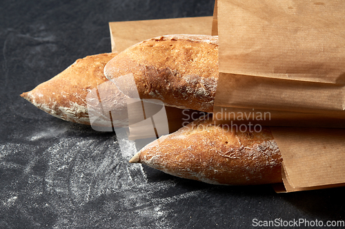 Image of close up of baguette bread in paper bags on table