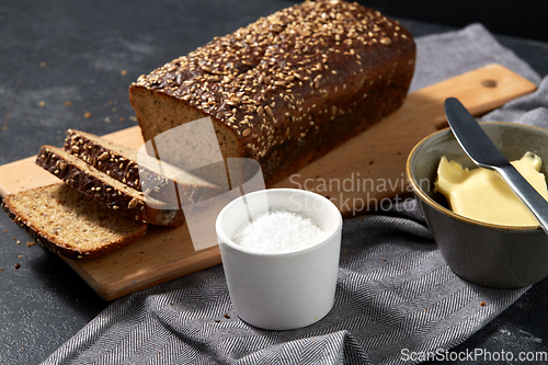 Image of close up of bread, butter, knife and salt on towel