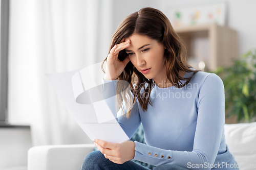 Image of stressed woman with paper sheet at home