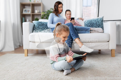 Image of happy girl with tablet pc and family at home