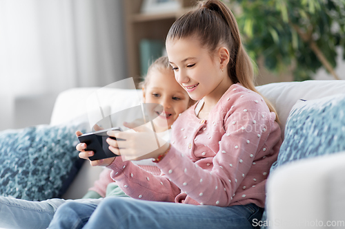 Image of happy little girls or sisters with phone at home