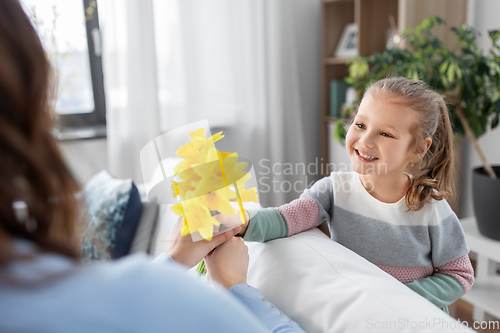 Image of happy daughter giving daffodil flowers to mother