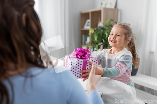 Image of happy daughter giving present to mother at home