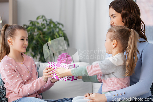 Image of girl giving present to younger sister at home