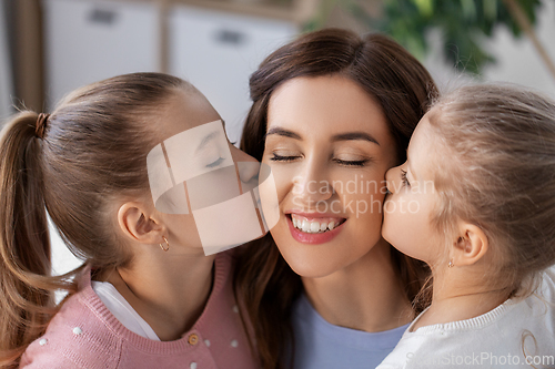 Image of happy mother and two daughters kissing her at home