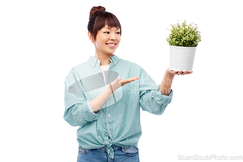 Image of happy smiling asian woman holding flower in pot