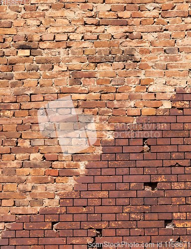 Image of restored by modern brick, part of the old wall of a building made of red brick, close-up with a curving line of restoration