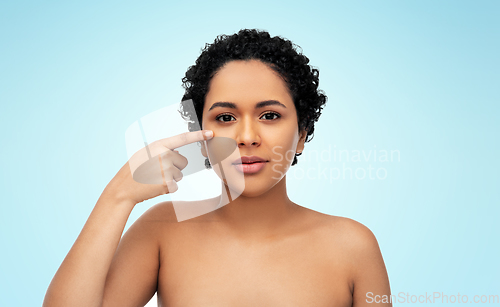 Image of young african american woman pointing to her face