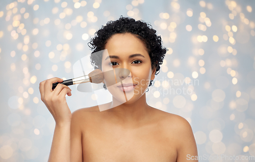 Image of woman with make up brush applying blush to face