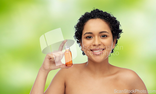 Image of happy african american woman with bottle of serum