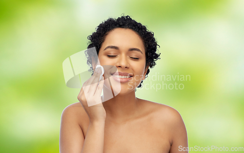 Image of happy african woman cleaning face with cotton pad