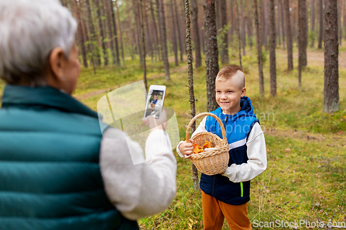 Image of grandmother photographing grandson with mushrooms