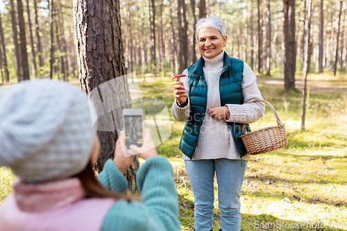 Image of granddaughter photographing grandma with mushrooms