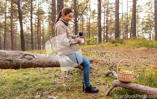 Image of asian woman with mushrooms drinking tea in forest