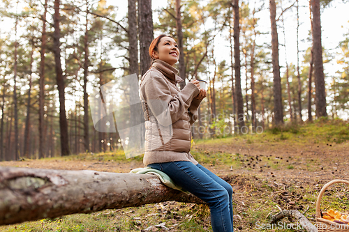 Image of asian woman with mushrooms drinking tea in forest