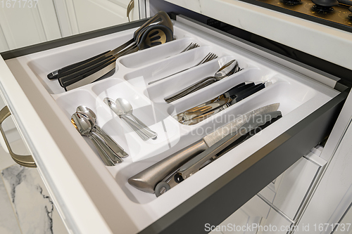 Image of Open drawer with cutlery at modern white woden kitchen in classic style