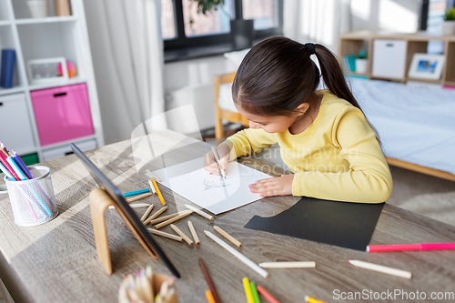 Image of little girl drawing with coloring pencils at home