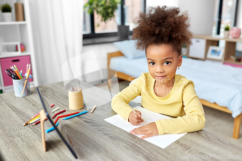 Image of little girl drawing with coloring pencils at home