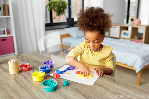 Image of little girl with modeling clay playing at home