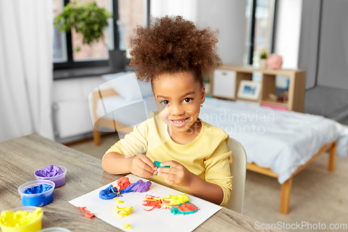 Image of little girl with modeling clay playing at home